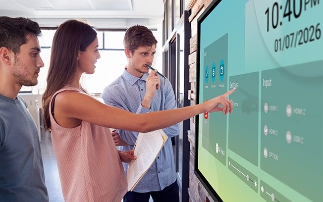 Three people using the launcher on a Sharp LB3 large-format interactive display.