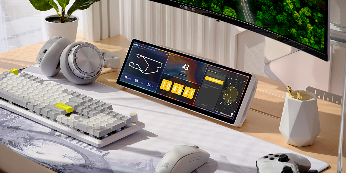 A white CORSAIR XENEON EDGE on a desk displays several widgets beneath a larger monitor.