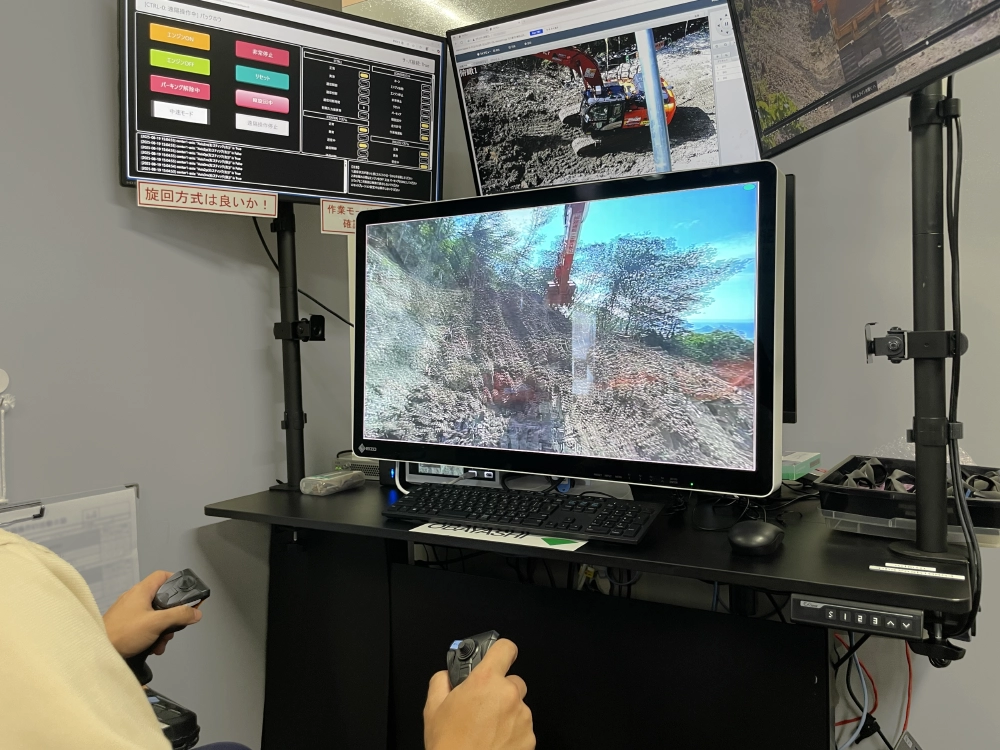 Remote construction operator in Kimitsu using an EIZO 3D display and control joysticks.