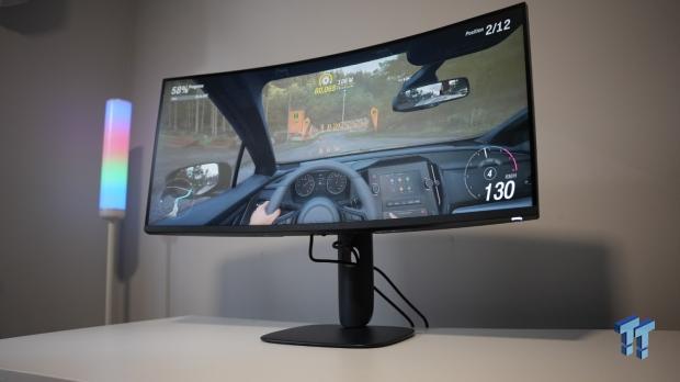 Curved Alienware monitor displaying a racing game, with the TweakTown watermark