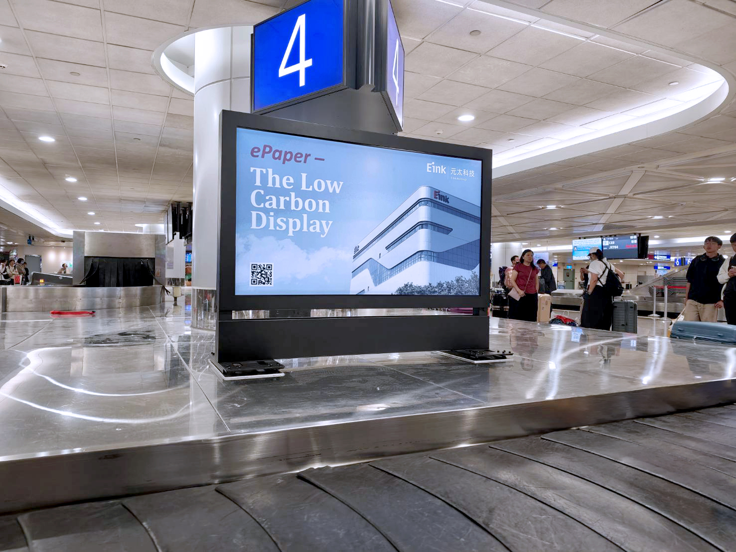 A 75-inch E Ink advertising display installed on a baggage carousel at Taoyuan International Airport, with the original E Ink branding visible.